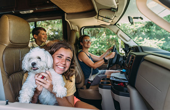 Family sits in their RV together while a girls holds up her dog.