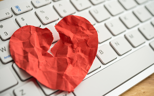 Broken heart made out of paper on a keyboard