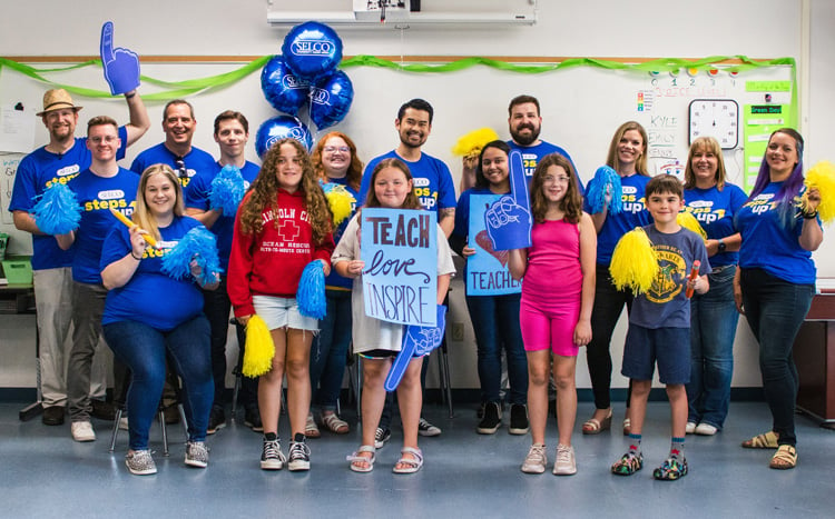 SELCO community credit union employees standing in a classroom celebrating educators. 