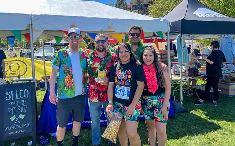 SELCO Employees standing at the puppy pit stop at pool pedal paddle.