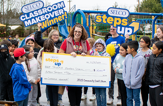 SELCO employees delivering a grant check to a classroom makeover winner. 