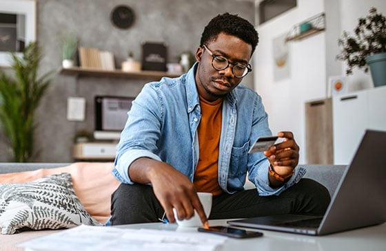 Person reviewing account information on a smartphone and laptop while using tools to protect sensitive personal and financial information online.