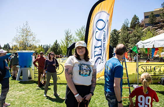 Woman standing in front of SELCO community credit union banner.