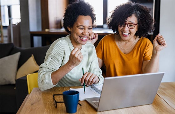 Happy couple sitting in front of a computer excited.