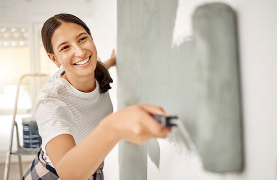 Homeowner painting an interior wall while financing home improvement projects with a SELCO Home Equity Line of Credit loan.