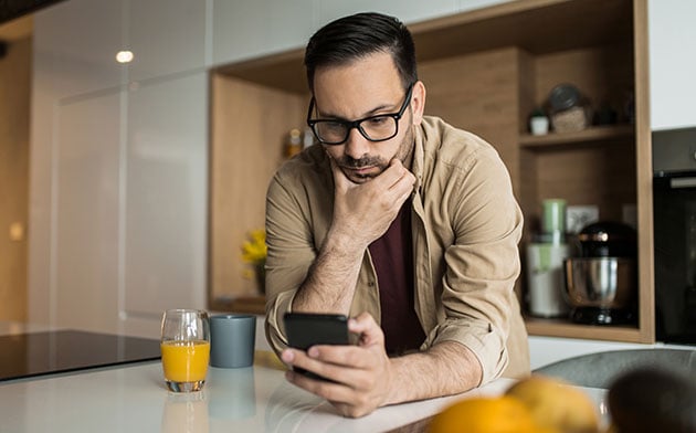 Man looking at his phone figuring out how to protect his sensitive information. 