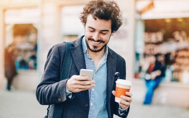 Guy smiling and looking at his phone.
